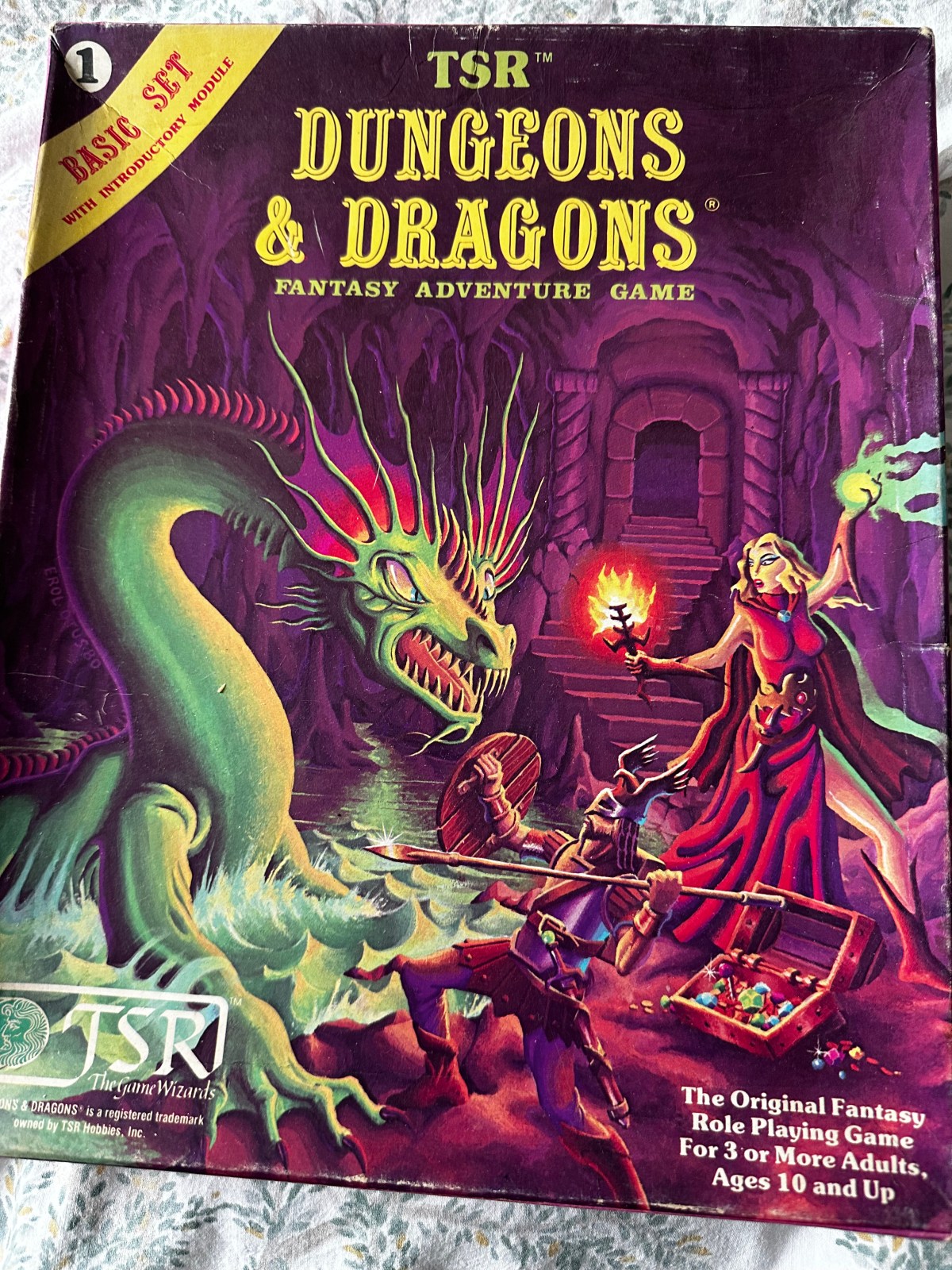 The front cover of the Moldvay Basic D&D Boxed Set. A green serpent attacks a sorceress in red in dungeon surroundings.